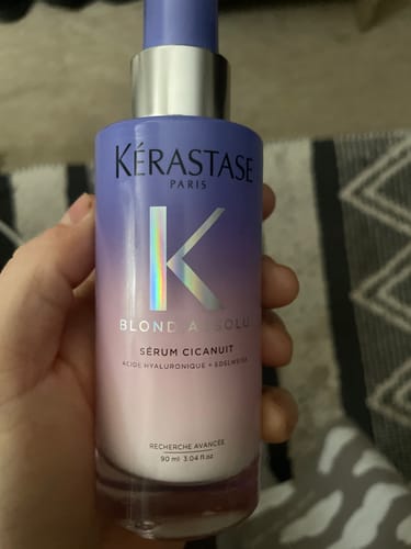 A customer holds their bottle of Kérastase Blond Absolu Cicanuit serum, showing its purple gradient design.