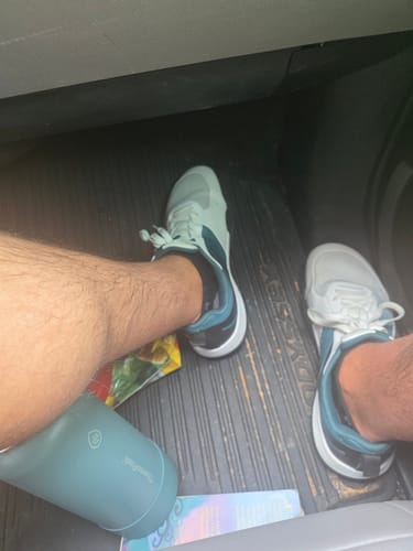 Customer wearing the light-colored CUURT Muuv court shoes with dark accents on the heel, seen from above in a car.