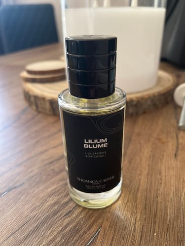 Customer's bottle of Lilium Blume Eau de Parfum with its black label and cap, sitting on a wooden table.