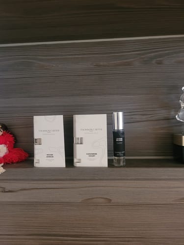 Customer's Cashmere Court Eau de Parfum box and a small perfume bottle arranged on a wooden shelf.