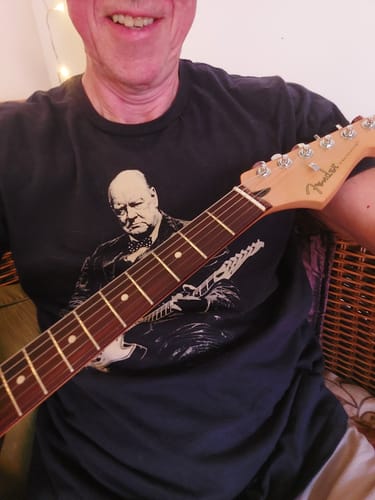 Reviewer wearing the dark Churchill Rock T-Shirt while holding an electric guitar.