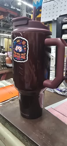 Customer's cinnamon Thicc Buddy 50oz mug with its lid, handle, and straw on a workbench.