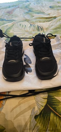 A reviewer's pair of black CUURT Muuv court shoes with wide toe boxes, resting on a bag.