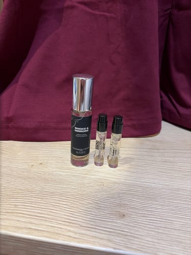Reviewer's Smoke & Mirrors Eau de Parfum bottle and two smaller sample vials on a wooden surface.