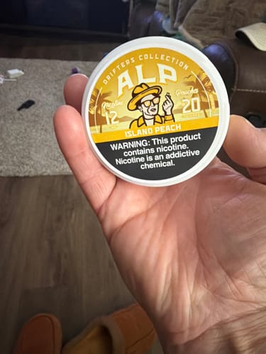 Customer holding a round tin of Drifters Island Peach Nicotine Pouches in their hand.