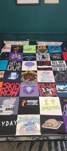 Customer's colorful Project Repat T-Shirt Quilt with various graphic tees spread out on a bed.