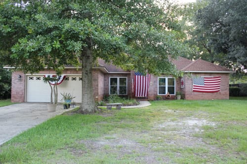 Customer's front view of their home, decorated with a vertically hung Heavy Duty American Flag and another flag.