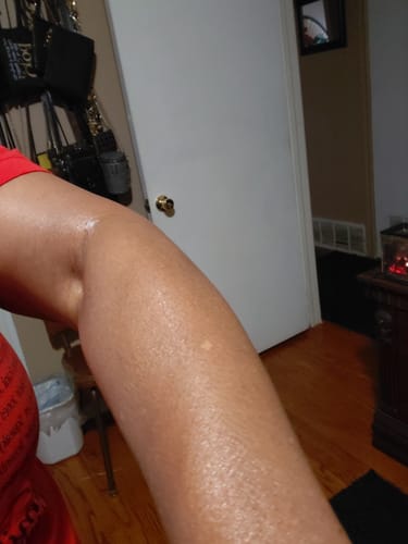 A customer's arm with a visible, soft glow after applying BODY GLAZE.
