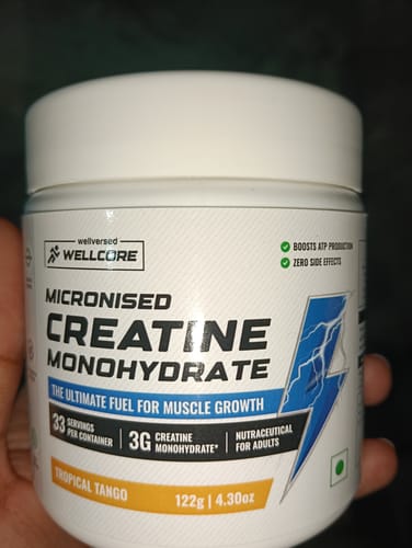 Customer holding a white jar of Wellcore Creatine Monohydrate in the Tropical Tango flavor.