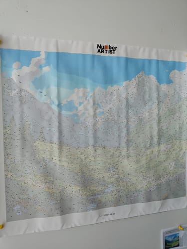 Customer's 'Breathtaking View' paint-by-numbers canvas pinned to a wall. The sky section is partially painted blue.