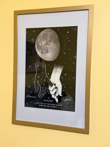 Customer's personalized memorial poster shown in a matted gold frame, hanging on a yellow wall in their home.