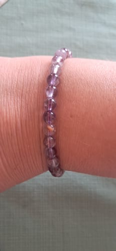 Gros plan du bracelet Auralite 23 6mm d'un client, montrant ses perles violettes et lumineuses.