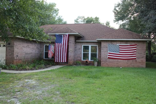 Customer's home with the new Heavy Duty American Flag hung vertically, shown next to an older flag for comparison.