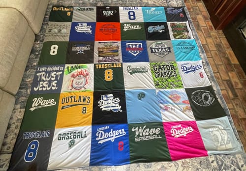Customer's finished Project Repat T-Shirt Quilt spread out, showing a colorful grid of sports and memory shirts.