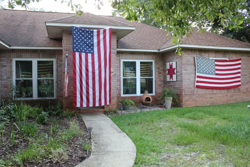 Close-up of the customer's new Heavy Duty American Flag hanging vertically on their brick house next to the front door.