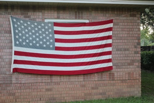 Customer's older, historical flag hung on a brick wall, shown for comparison with the new Heavy Duty American Flag.