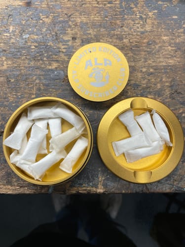 Reviewer's open limited edition gold container of Tropical Fruit Nicotine Pouches with the lid used as a separate holder.
