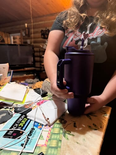 A person holding the large, purple Thicc Buddy 50oz mug indoors.