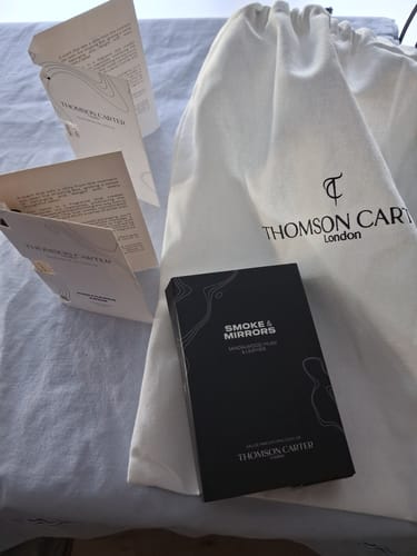 Customer's Smoke & Mirrors Eau de Parfum box with its white branded pouch and informational papers.