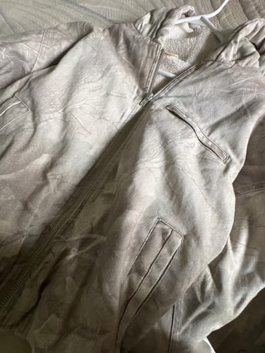 Reviewer's Camo Bronco Jacket in a light camo print, shown close-up and unzipped on a hanger.