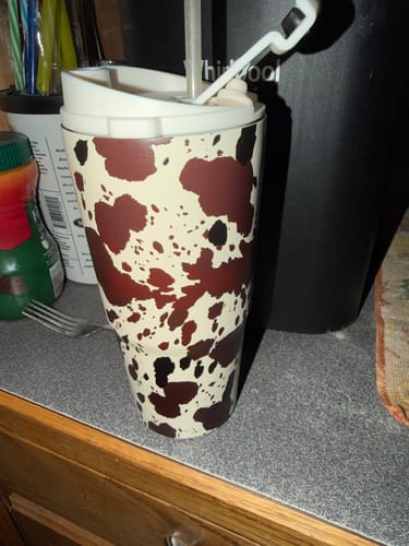 Customer's To-Go Buddy insulator in a cow print design, sitting on a kitchen counter.