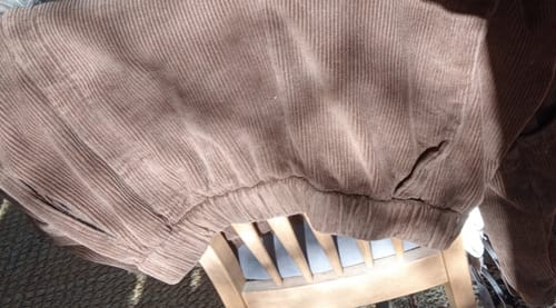 Reviewer's close-up of their brown corduroy harem pants, showing a flaw in the tucks near the pocket.
