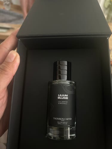 Customer holding the open black box revealing the Lilium Blume Eau de Parfum bottle inside.