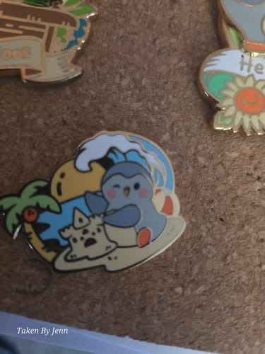 Customer's cute Little Escape Pin showing a penguin building a sandcastle on a beach, pinned to a corkboard.