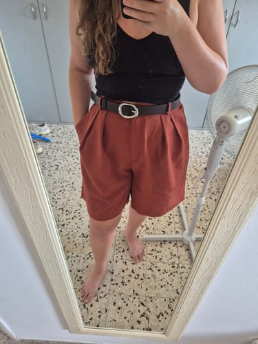 לקוחה בסלפי מראה לובשת את מכנסי הברק בצבע חמרה עם גופייה שחורה וחגורה.