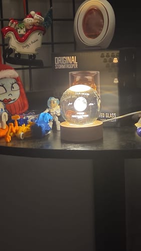 Reviewer's personalized crystal ball night light glowing brightly on a dark shelf among other decorative items.