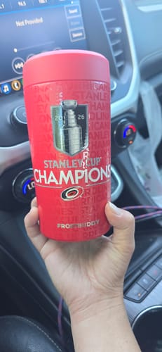 Customer holding their red Carolina Hurricanes Stanley Cup Champions Universal Buddy in a car.