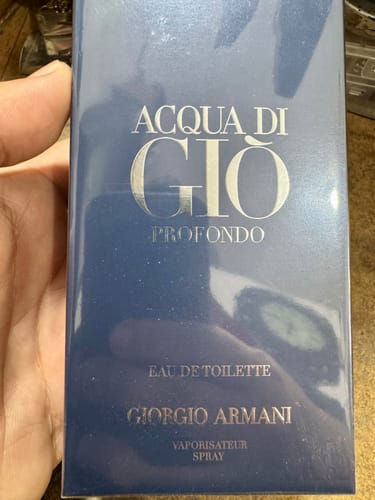 Primer plano de un cliente sosteniendo la caja azul y sellada del perfume Acqua Di Gio Profondo.