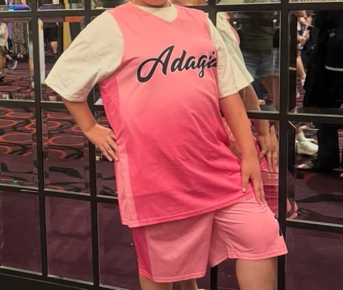 Customer posing in the light pink gradient basketball jersey and shorts set. The jersey has the custom name 'Adagio' printed on it.