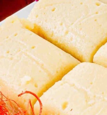 Customer's close-up of soft Rehmat-e-Shereen Burfi pieces with a red saffron garnish.