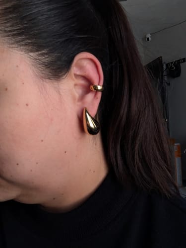 Clienta mostrando el Ear Cuff Sally dorado en el cartílago de la oreja.