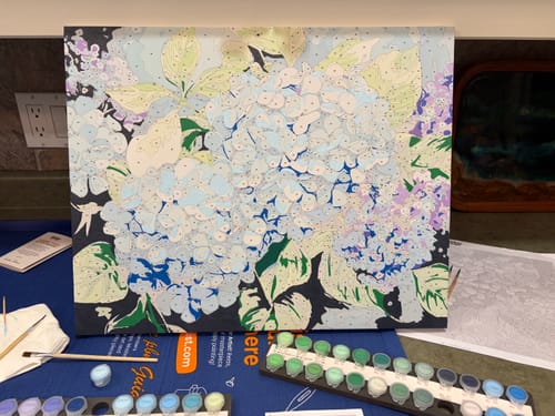 Reviewer's Blue Hydrangea paint-by-numbers canvas, partially painted, with paint pots visible below.