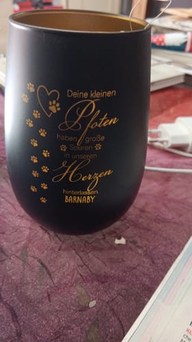 Ein Kunde zeigt das personalisierte schwarze Trauerlicht mit der goldenen Gravur „Barnaby“ und Pfotenabdrücken.