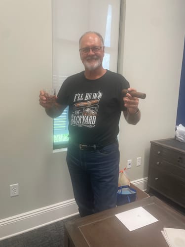 A happy reviewer wears the black 'I'll Be In The Backyard' shirt while holding a cigar and a drink.