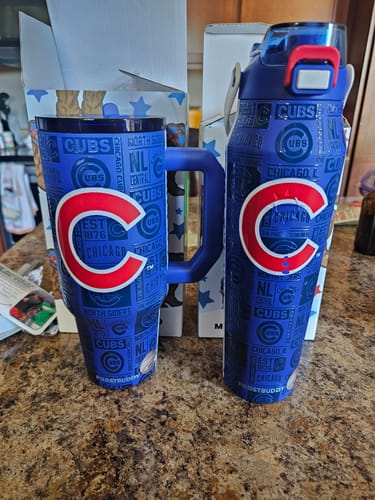 Customer's blue Thicc Buddy 40oz tumbler with a Chicago Cubs design next to a matching water bottle on a counter.