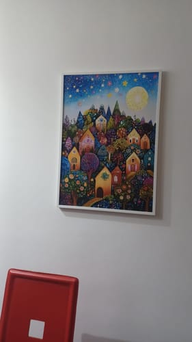 Cliente mostra il quadro 'Colline stellate' con colori brillanti, incorniciato e appeso a una parete.