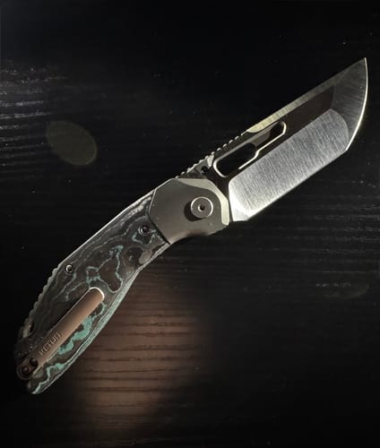 Customer's Ketuo Yakuza knife with a unique green and black camo carbon handle laid on a dark surface.