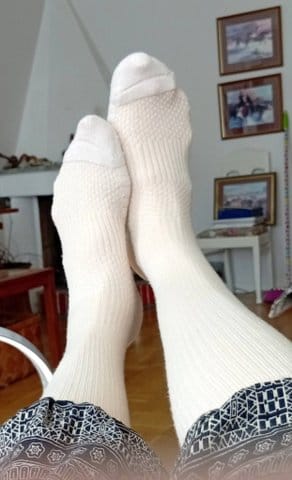 Recensent med fötterna upplagda, iklädd vita Diasocks Stödstrumpor inomhus.