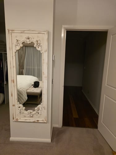 Reviewer's Lucien Ornate Floor Mirror with a distressed finish, mounted on a bedroom wall.