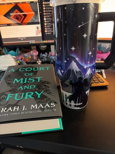 Customer's Thicc Buddy 40oz Nightfall mug on a desk next to the book 'A Court of Mist and Fury'.
