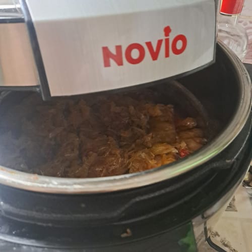 Close-up of a customer's Multicooker Novio SteelCook with the lid open, showing homemade stew inside.