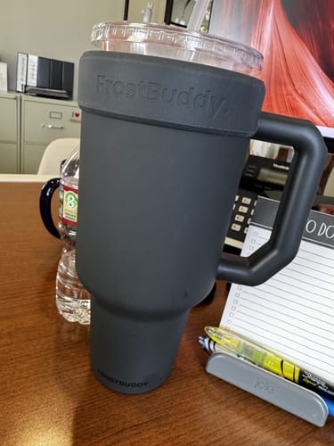 Customer's ash-colored Thicc Buddy 50oz mug holding a separate drink cup on an office desk.