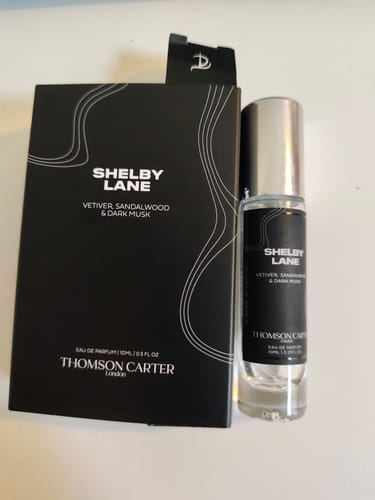 Reviewer's Shelby Lane Eau de Parfum bottle with a silver cap, placed beside its elegant black box.
