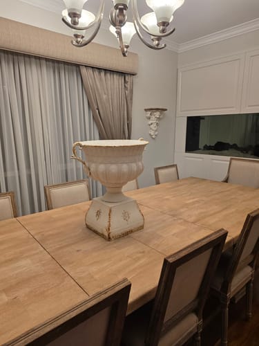 Customer's antique white Héloïse Urn Planter on a plinth, styled as a centerpiece on a dining room table.