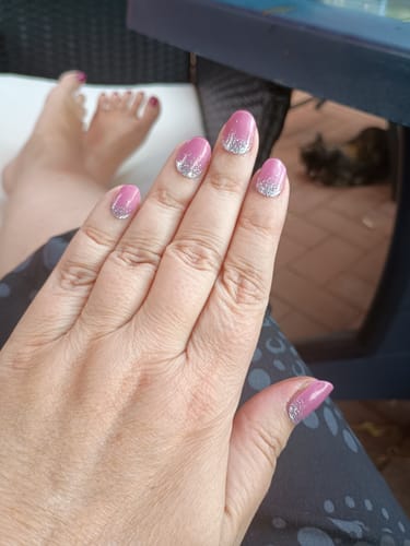 Kundenfoto einer Hand, die die aufgetragenen „Glitter Dizzle“ UV-Gelnägel in Rosa mit Silberglitzer-Ombré zeigt.