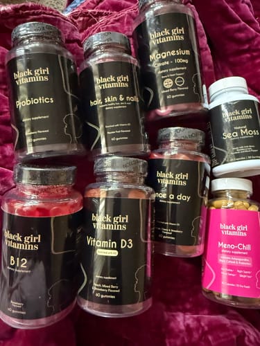Customer's Probiotics vitamins shown with several other Black Girl Vitamins products on a bed.